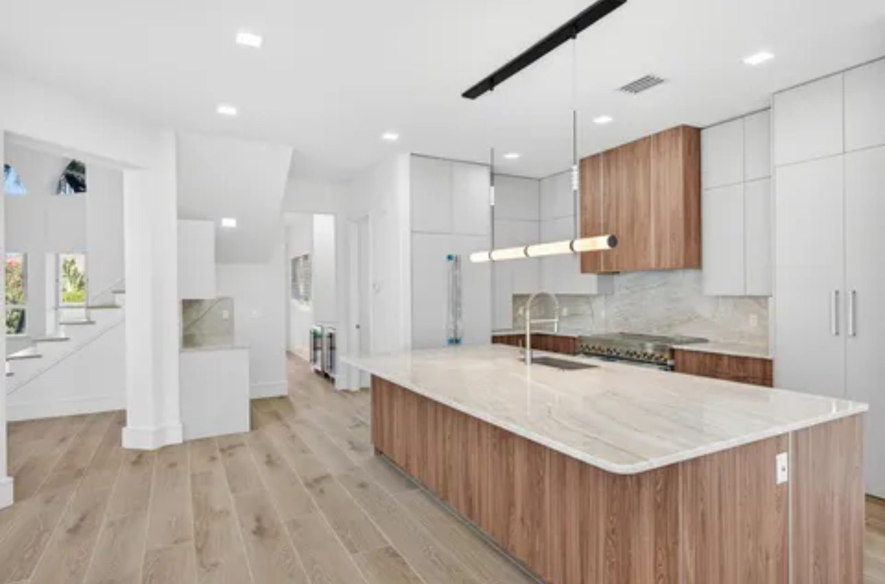 Kitchen remodel with custom white oak cabinetry, marble waterfall island and integrated lighting in Fort Myers home